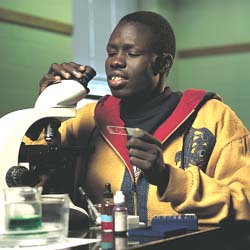 Moses Ajou about to view a sample through a microscope